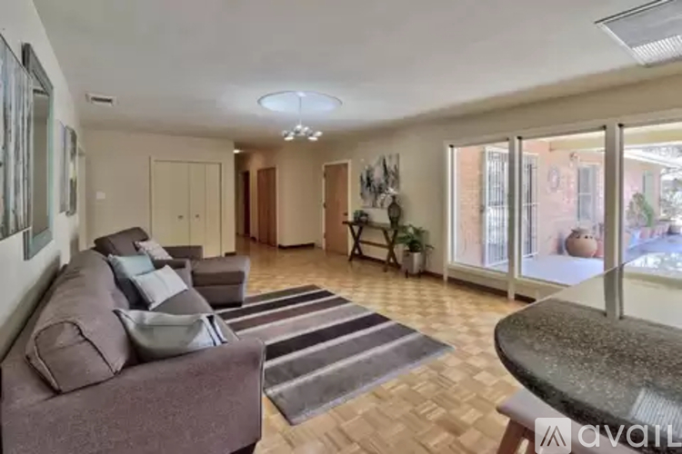 A living room with a brown couch and a glass table.