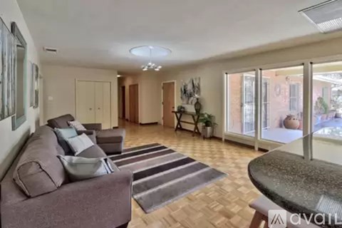 A living room with a brown couch and a glass table.