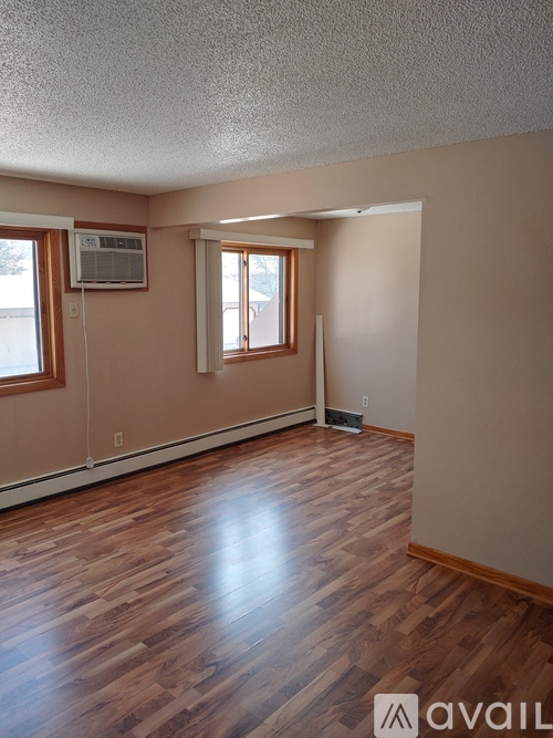 A room with wooden flooring and a window with blinds.