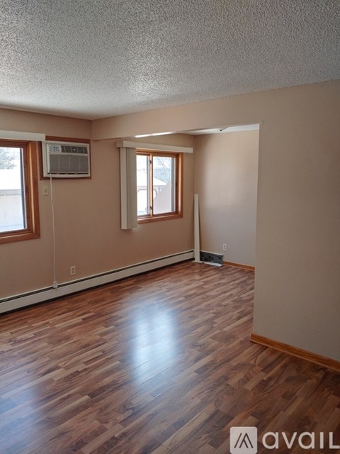 A room with wooden flooring and a window with blinds.