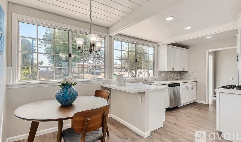 A kitchen with a table and chairs in front of a window.