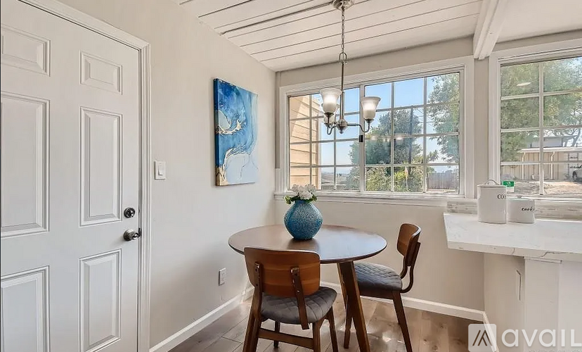 A dining room with a table, chairs, and a painting on the wall.