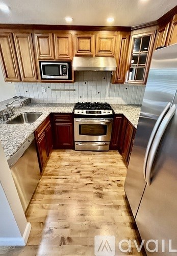 A kitchen with wooden cabinets and a stainless steel refrigerator.