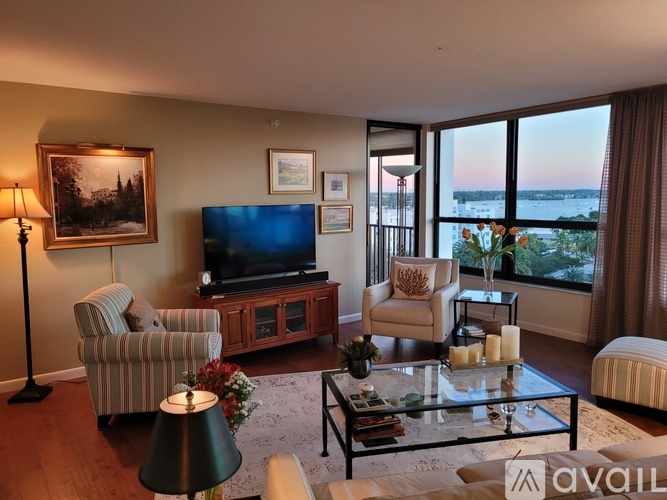 A living room with a television, a sofa, a chair, a coffee table, and a painting on the wall.
