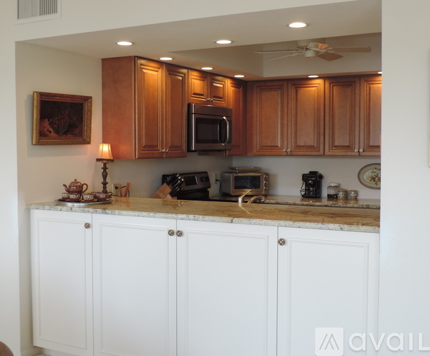 A kitchen with white cabinets and a countertop with a microwave, oven, and other appliances.