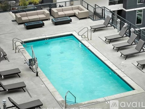A pool surrounded by lounge chairs and tables.