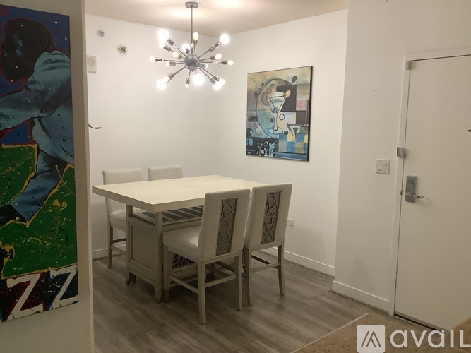 A dining room with a white table and chairs and a painting on the wall.