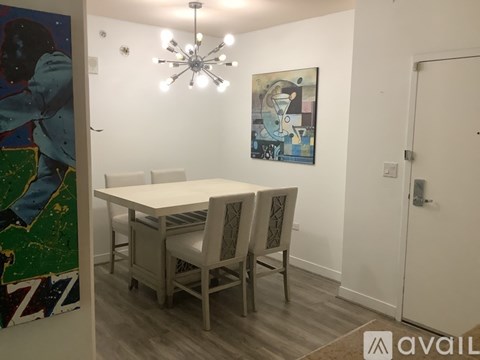 A dining room with a white table and chairs and a painting on the wall.