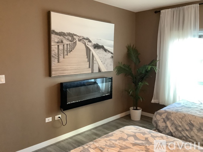 A bedroom with a large picture on the wall and a bed with a patterned blanket.