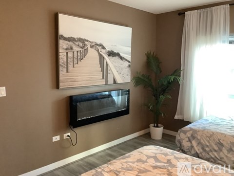A bedroom with a large picture on the wall and a bed with a patterned blanket.