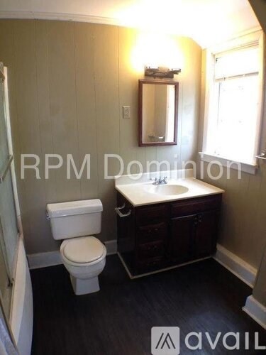 A bathroom with a toilet, sink, and mirror.