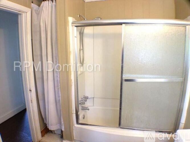 A white shower stall with a glass door is in a bathroom.