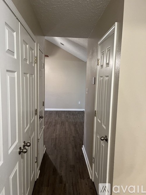 A hallway with white doors and dark wood floors.