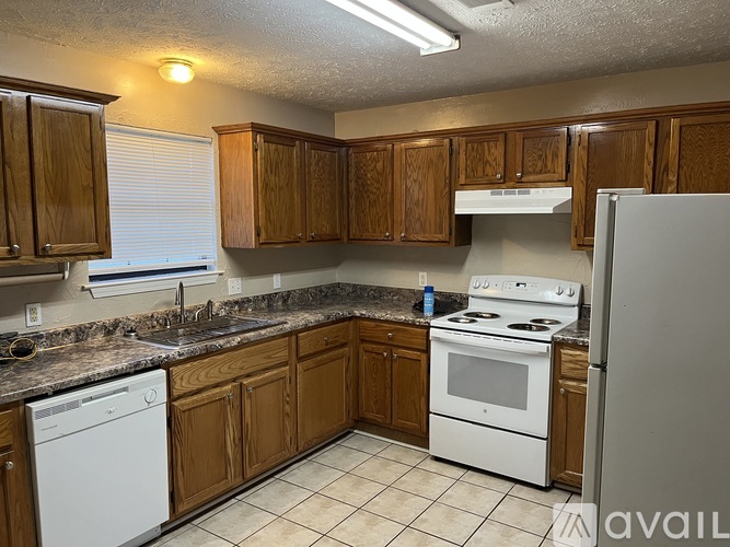 A kitchen with white appliances and brown cabinets.