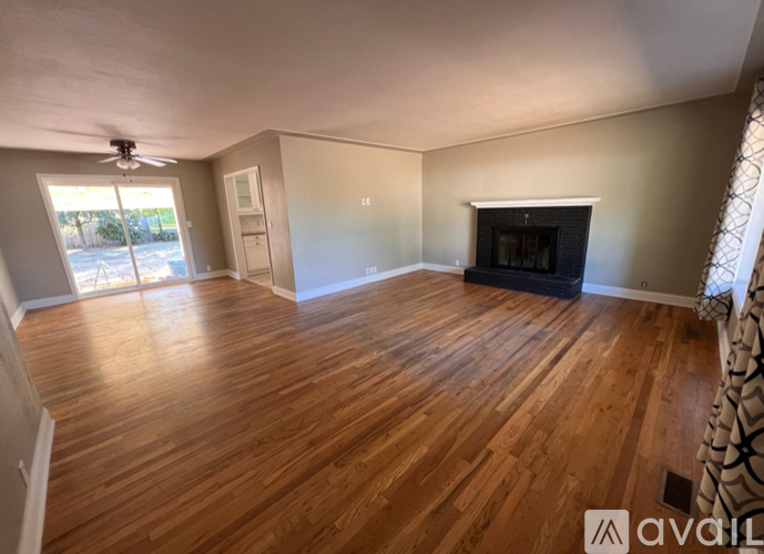 A room with wooden flooring and a fireplace.