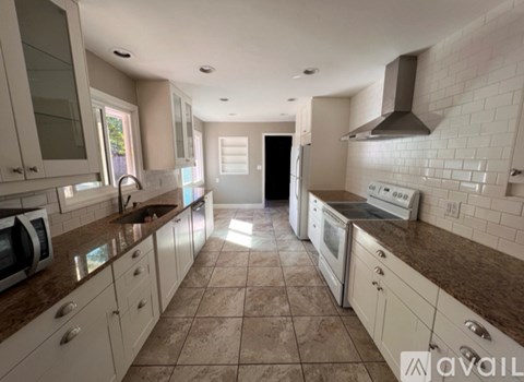 A kitchen with white cabinets and brown countertops.