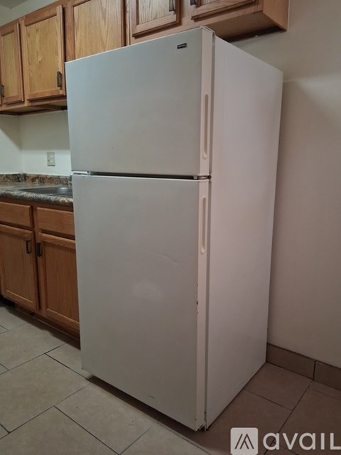 A white refrigerator in a kitchen with wooden cabinets.