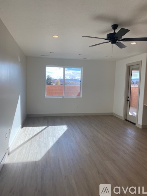 A room with a ceiling fan and a window overlooking a red brick building.