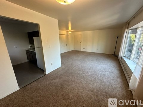 A spacious room with a carpeted floor and a window on the right side.