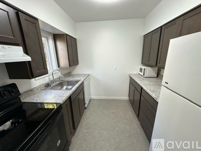 A kitchen with dark brown cabinets and a black stove top oven.