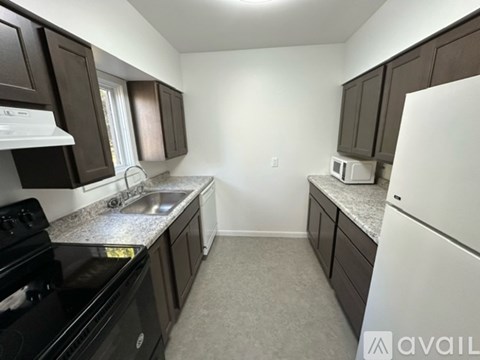 A kitchen with dark brown cabinets and a black stove top oven.