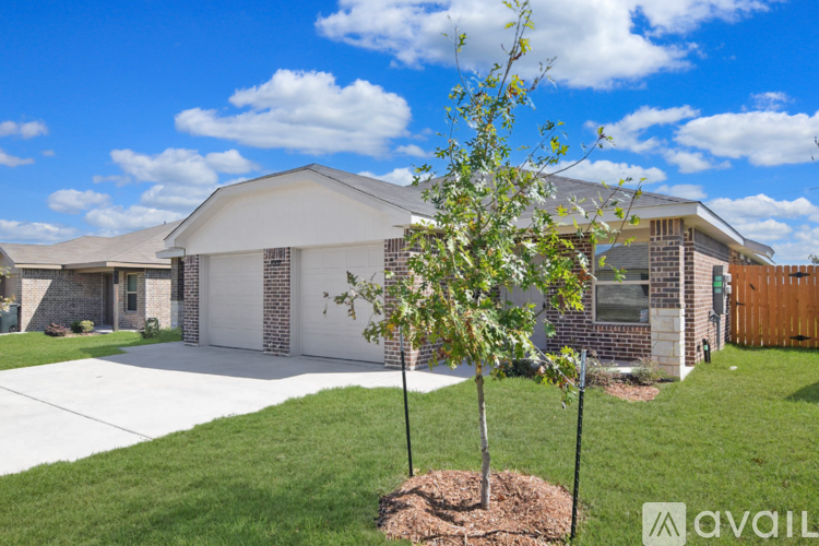 A house with a white garage door and a tree in front.