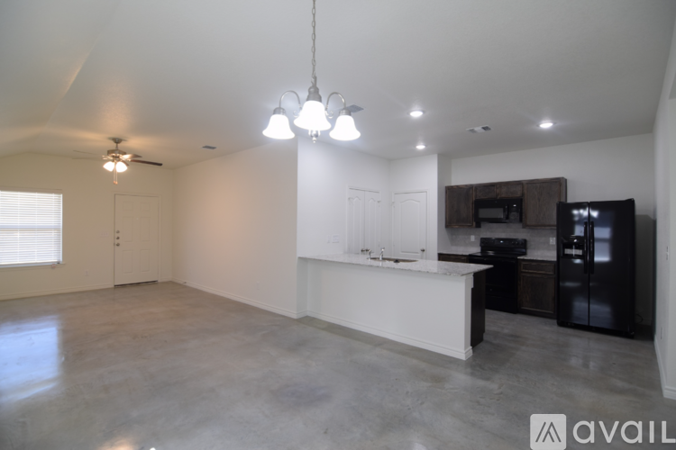 A spacious kitchen with a black refrigerator and white countertops.