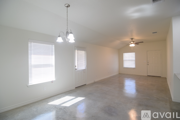 A spacious room with a hanging light fixture and a ceiling fan.