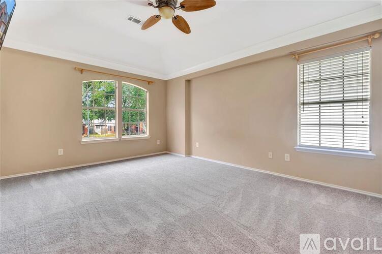 A spacious room with a ceiling fan and carpeted floor.