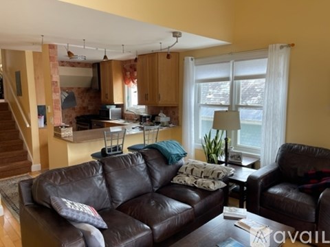 A living room with brown leather couches and a kitchen area in the background.