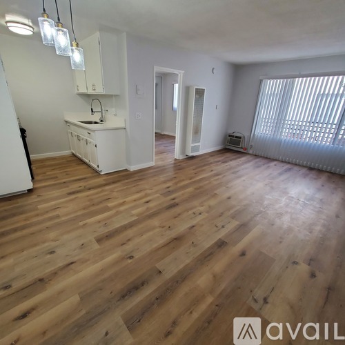 A spacious room with wooden flooring and white walls.