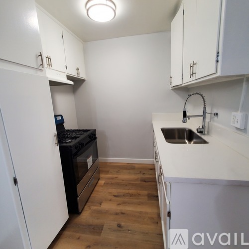 A kitchen with white cabinets and a black stove top oven.