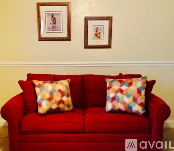 A red couch with two pillows on it.