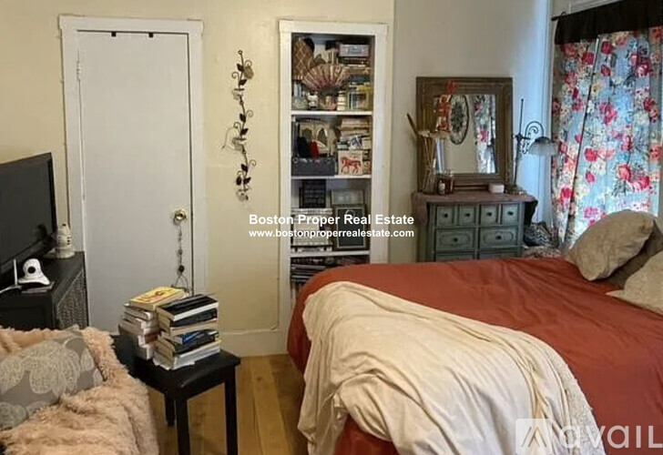 A bedroom with a bed, nightstand, and a bookshelf with various items.