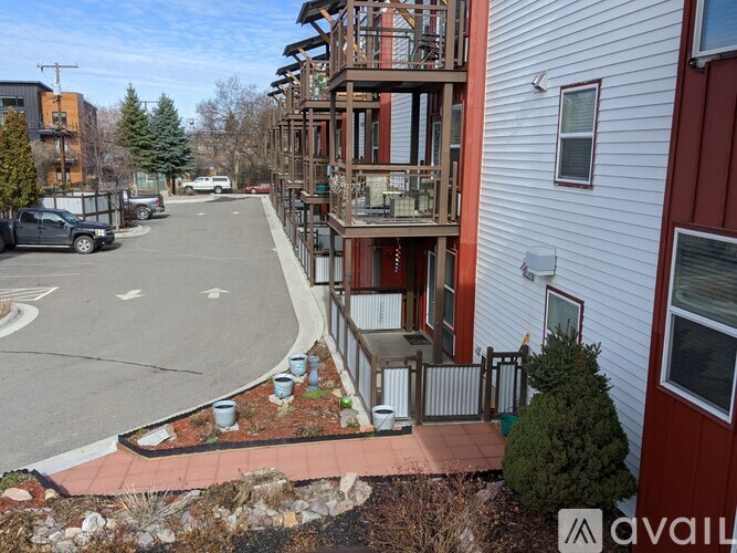 A view of a street with a building on the right and a car parked on the left.