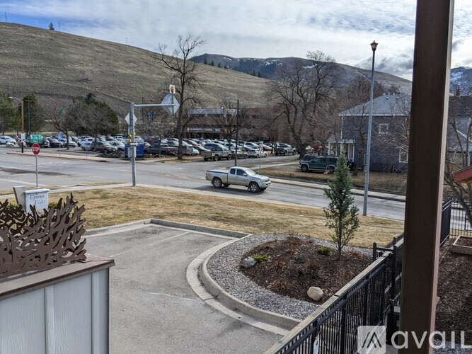 A parking lot with cars and a hill in the background.