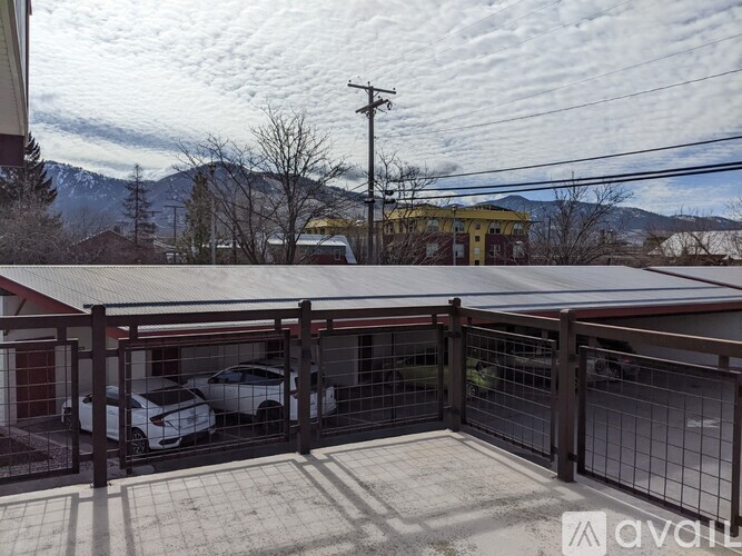 A carport with a metal roof and a fence in front of a house with a mountain in the background.
