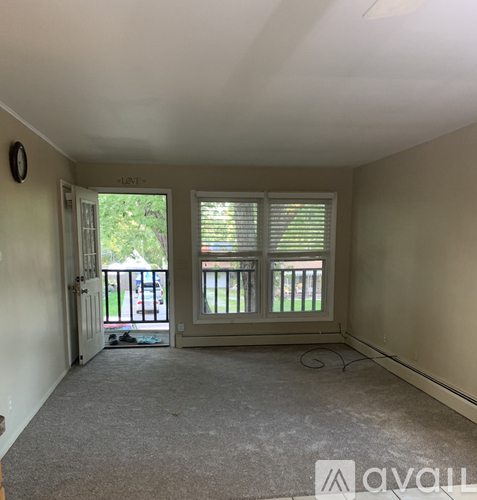 A room with a carpeted floor and a window with blinds.