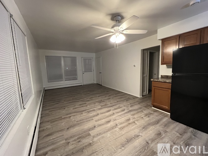 A spacious room with a ceiling fan and wooden flooring.