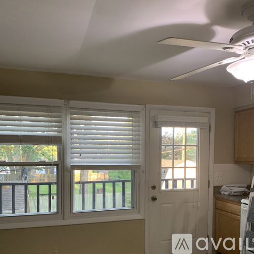 A room with a ceiling fan and a window with blinds.