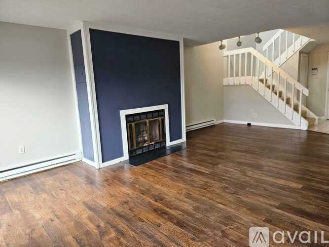 A living room with a fireplace and a staircase in the background.