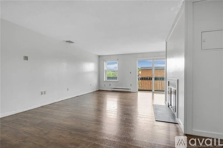 A spacious room with wooden flooring and a large window.
