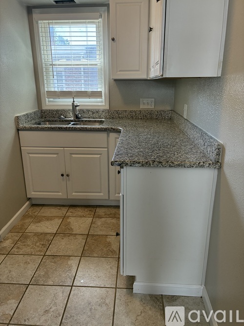 A kitchen with granite countertops and white cabinets.