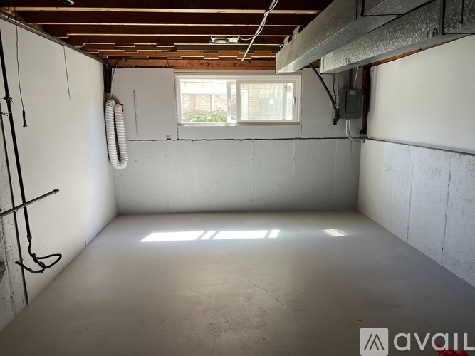 A spacious empty room with a window and a white wall.