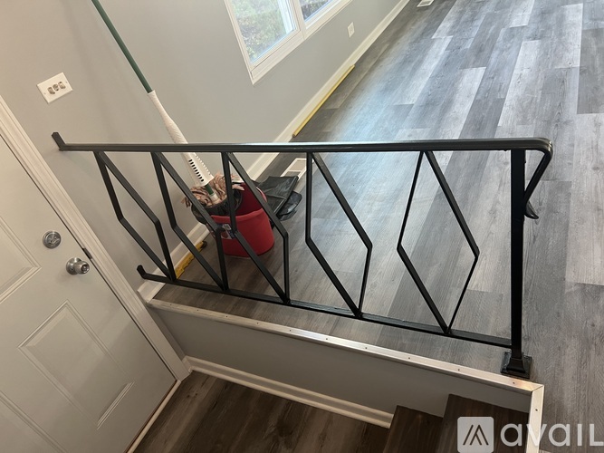 A black metal railing on a staircase with a red vacuum cleaner on the steps.