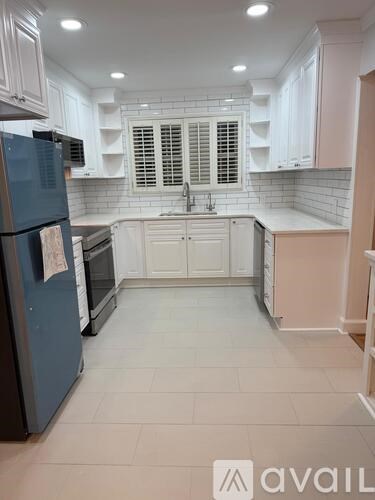 A kitchen with white cabinets and a black fridge.