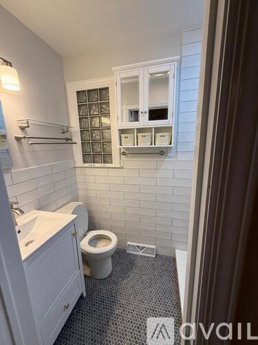 A small white bathroom with a toilet, sink, and a cabinet above the toilet.