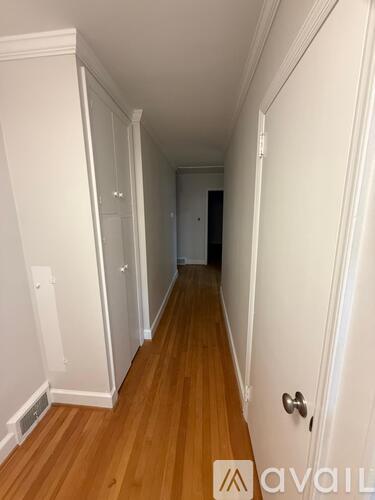 A hallway with wooden floors and white walls.