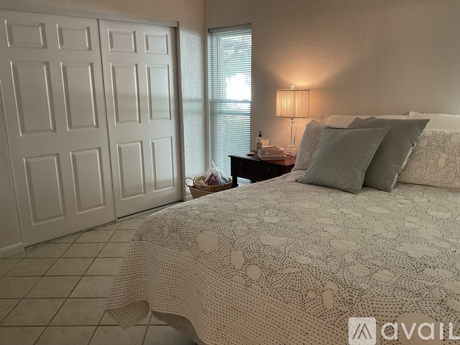 A bedroom with a bed, nightstand, and a basket on the floor.