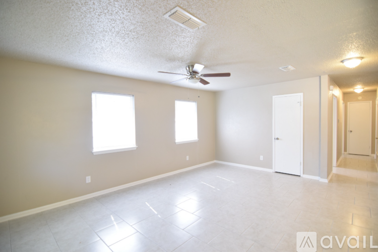 A spacious room with a ceiling fan and three windows.